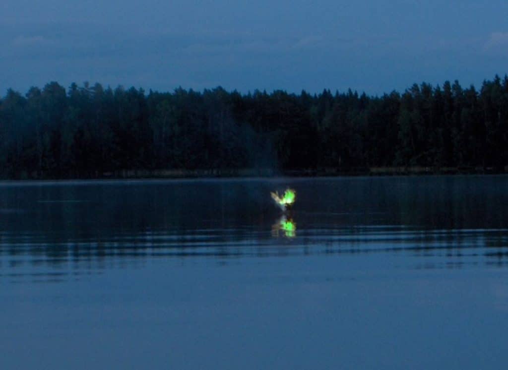 Fake Will-o'-the-Wisp image of a green light over a lake.